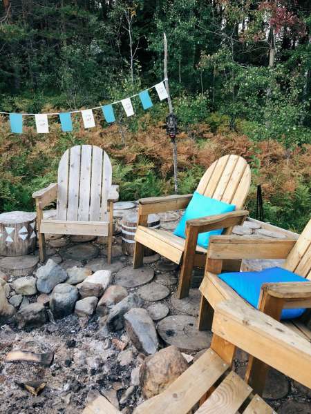 three brown wooden armchairs near bunting in front of green trees